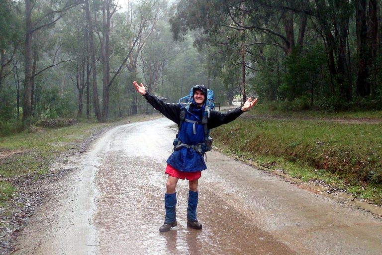 Hiker in rain jacket and overpants on a wet trail